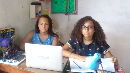 Irmãs Aimê e Aisha estudando juntas em casa.